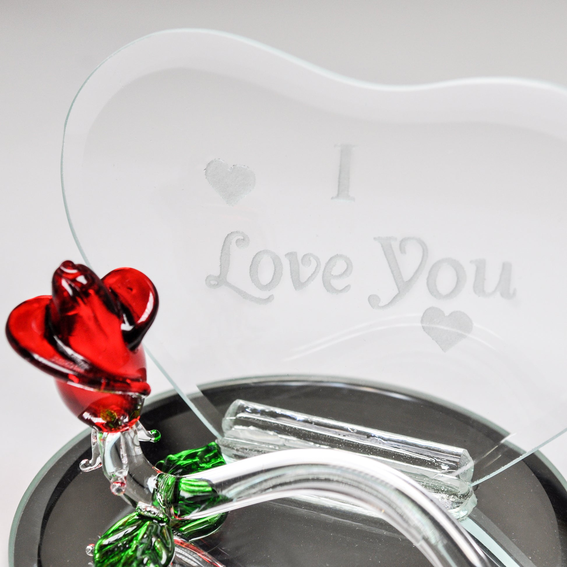 Crystal Castle Heart Shaped Glass plaque with glass rose and mirror base. The words " I love you" are engraved on the glass heart. Close up of red and green glass rose.
