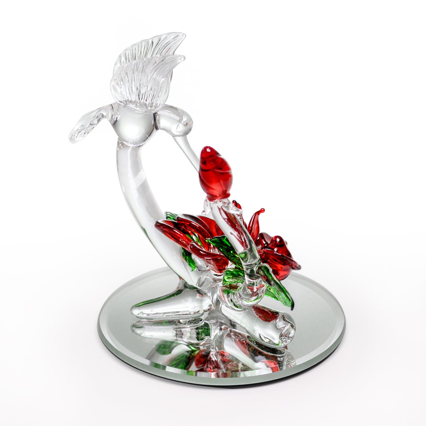 Crystal Castle Hummingbird flying over red and green glass flowers and flowers buds on a mirror base. Side View.